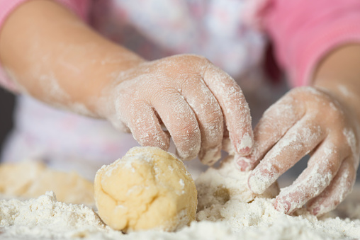 Little girl kneading dough.
