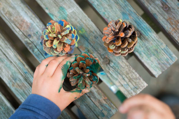 istock Child's hand painting pine cones 941140442