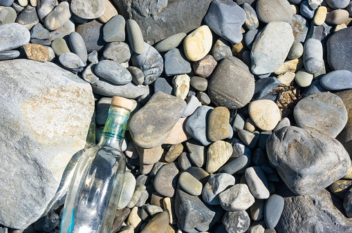 glass bottle washed up by the sea on a pebble beach