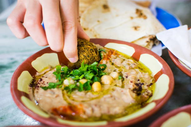 donna che mangia felafel e hummus con fagioli - consumption level foto e immagini stock