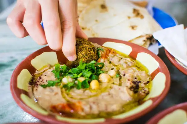 Woman eating felafel and hummus with beans in restaurant