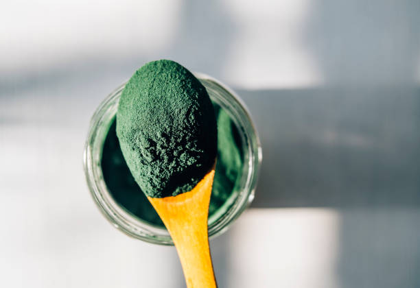 木のスプーンでスピルリナ パウダー - seaweed spirulina bacterium algae food ストックフォトと画像