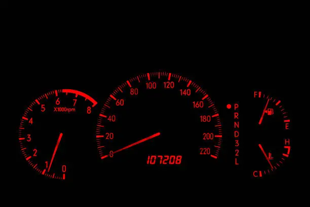 Closeup of an automobile dashboard at night. The dashboard glows orange. The speed scale does not indicate miles or kilometers, so it could be used for either.