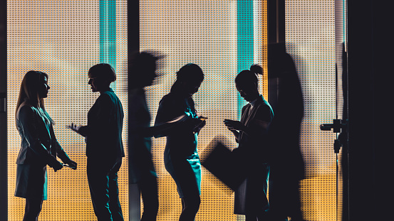 Silhouettes of a group of business people standing or walking in the office building