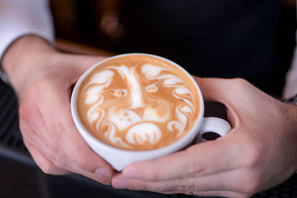 Barista in the bar holds a cup of coffee with a drawn lion