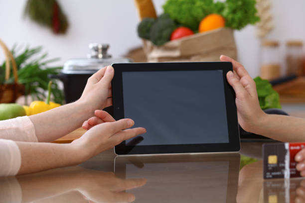 istock Closeup of human hands cooking in kitchen. Women discuss a menu using tablet computer. Copy space area at touch pad. Healthy meal, vegetarian food and lifestyle concepts 941171532