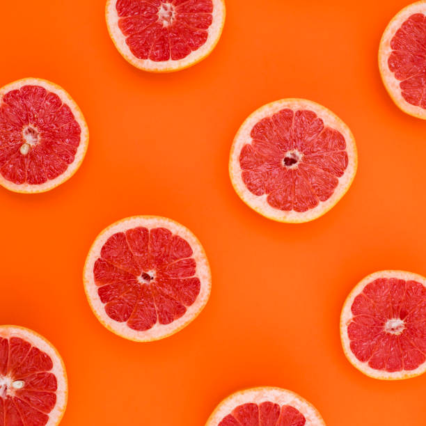 istock Background of grapefruit split in half and arranged on an orange background 941181228