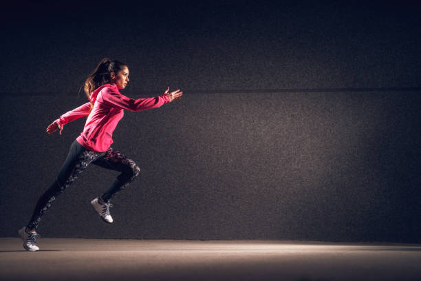 seitenansicht bewegung der jungen sexy attraktive gesunde fitness sportlich aktive schlankes girl mit sportbekleidung laufen vor der grauen wand in der nacht auf der straße. - fashion model beautiful power action stock-fotos und bilder