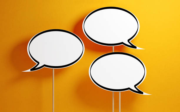 White chat bubbles with wooden sticks on yellow background. Horizontal composition with copy space.
