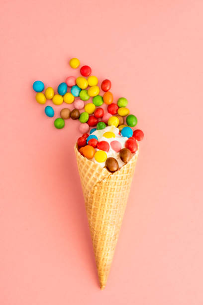 istock Ice cream in a waffle cone with colored candy toppings on a pink background 941187020