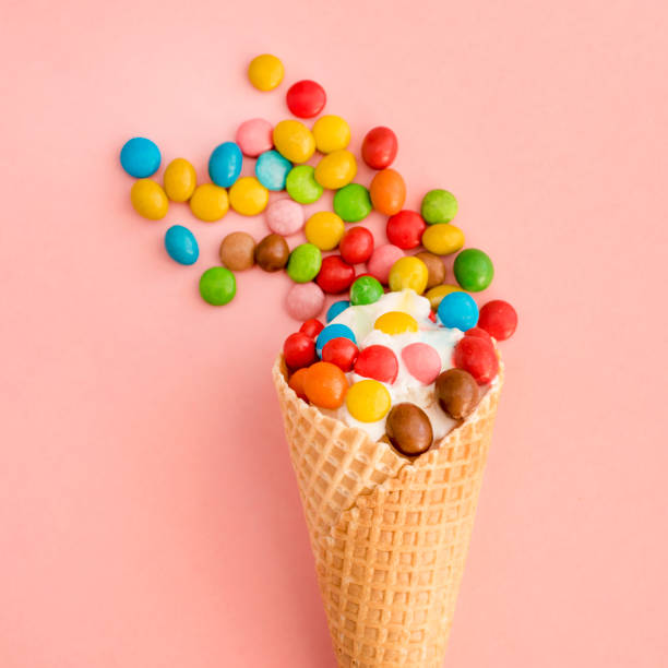 istock Ice cream in a waffle cone with colored candy toppings on a pink background 941187050