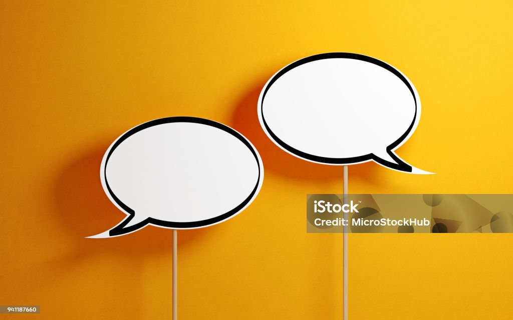 White Chat Bubbles With Wooden Sticks On Yellow Background White chat bubbles with wooden sticks on yellow background. Horizontal composition with copy space. Communication Stock Photo