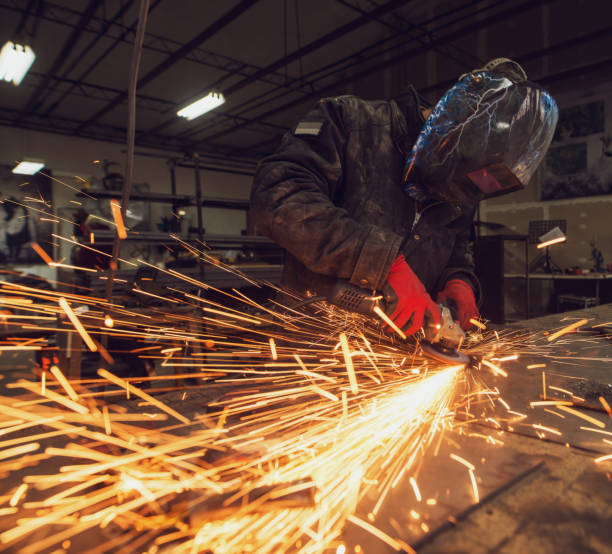 istock Craftsman sawing metal, sparkles around workshop. 941189900