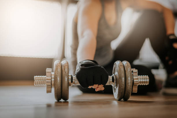 istock Woman picking up dumbbell on gym floor 941189912