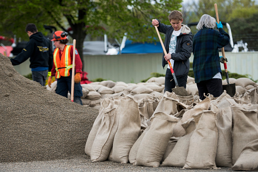 KELOWNA, CANADA - MAY 12, 2017: Volunteers work together to build sandbags at an emergency flooding station on May 12, 2017 in Kelowna, British Columbia, Canada.