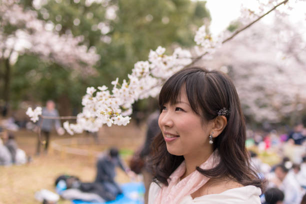 istock Young woman looking at cherry blossoms at hanami party 941193126
