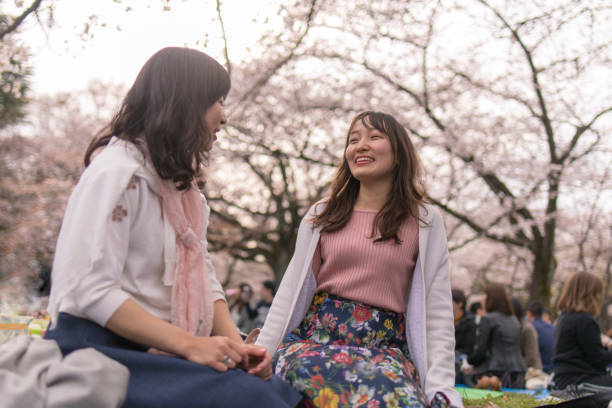 istock Young female friends talking under cherry blossoms 941193174