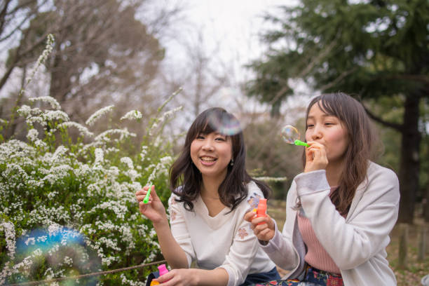 istock Young female friends blowing bubbles in public park 941193306