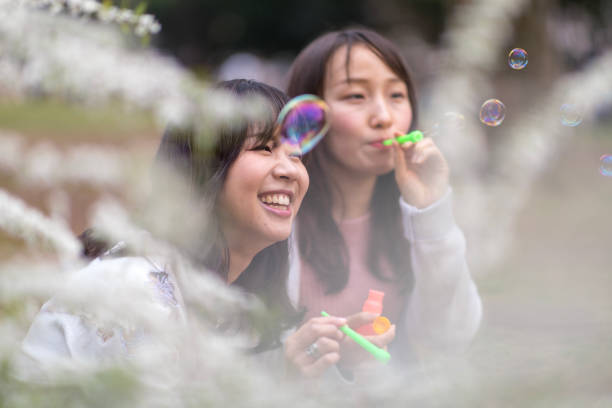 istock Young female friends blowing bubbles in public park 941193312