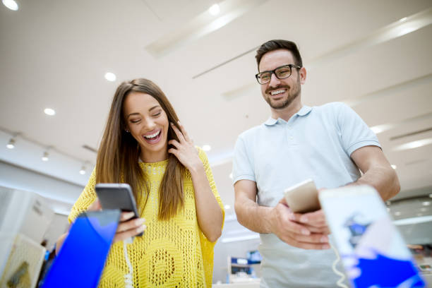 istock Satisfied charming young handsome love couple choosing a new mobile in a tech store. 941204566