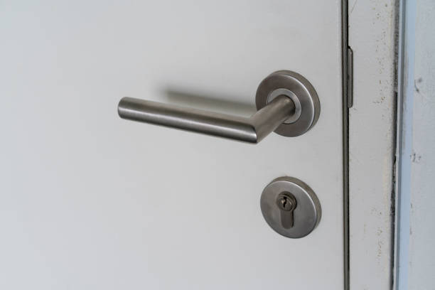 istock Chrome door handle and lock with key on white metal door 941206032