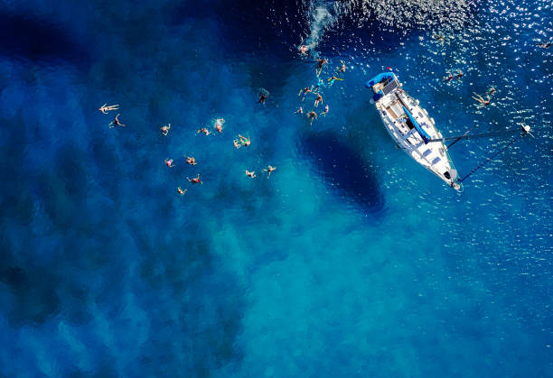 luftaufnahme des schönen blauen lagune am heißen sommertag mit segelboot. draufsicht des menschen sind schwimmen, um das boot herum. - barbados vacation stock-fotos und bilder