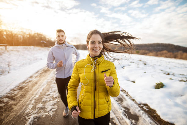 casal de esportiva atletas ativo executando com forte persistência na estrada na natureza de inverno da manhã. - desporto de inverno - fotografias e filmes do acervo