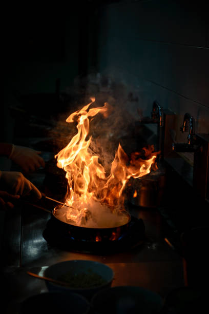 istock Chef cooking and doing flambe on food in restaurant kitchen 941233342