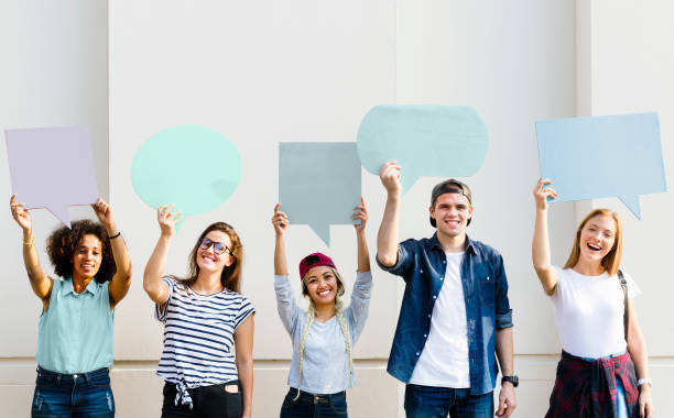istock Young adult friends holding up copy space placard thought bubbles 941234576