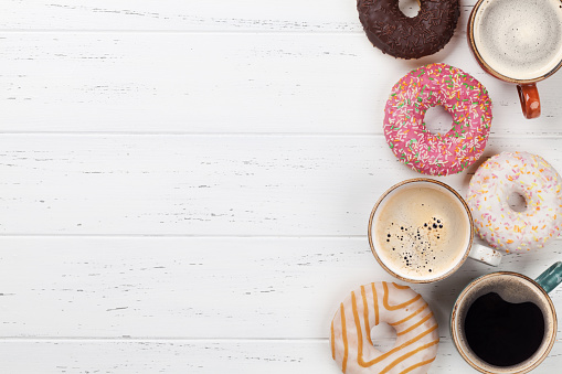 Coffee and donuts on wooden table. Top view with space for your text