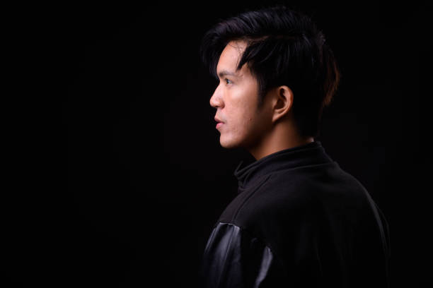 istock Young handsome Asian man against black background 941241246