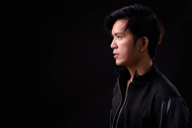 istock Young handsome Asian man against black background 941241248