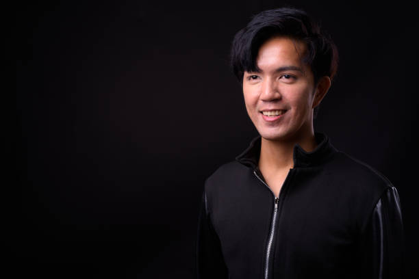 istock Young handsome Asian man against black background 941241286