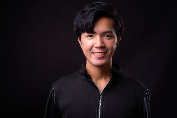 istock Young handsome Asian man against black background 941241394