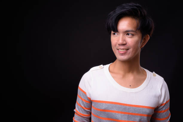 istock Young handsome Asian man against black background 941241576