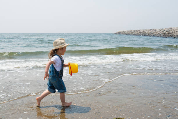 kleines mädchen spielt am strand - child asian ethnicity little girls toddler stock-fotos und bilder