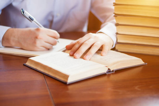 istock Closeup view of studying young caucasian man reading book and writing something. Preparing for exams in university library. 941255826