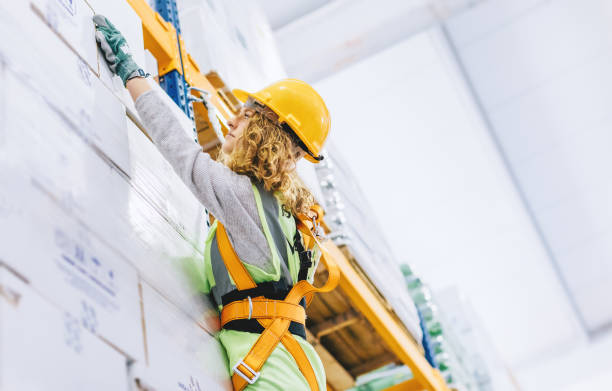 istock Young female manual worker hanging on a climbing rope in warehouse 941263532