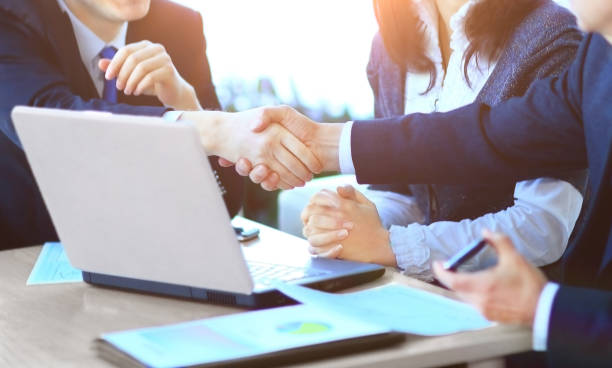 istock close up.businessmen shaking hands over a Desk 941264942