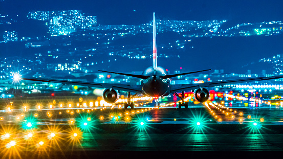 Airplane landing at airport at night, dark sky