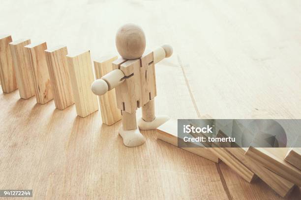 A Wooden Dummy Stopping The Domino Effect Retro Style Image Executive And Risk Control Concept Stock Photo - Download Image Now