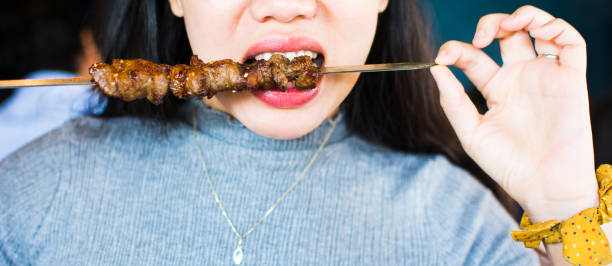 Woman eating barbeque close up Woman eating Chinese barbeque close up chinese ethnicity china restaurant eating stock pictures, royalty-free photos & images