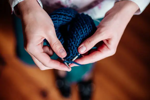 The woman knits woolen clothes. Knitting needles. Close-up. Natural wool.