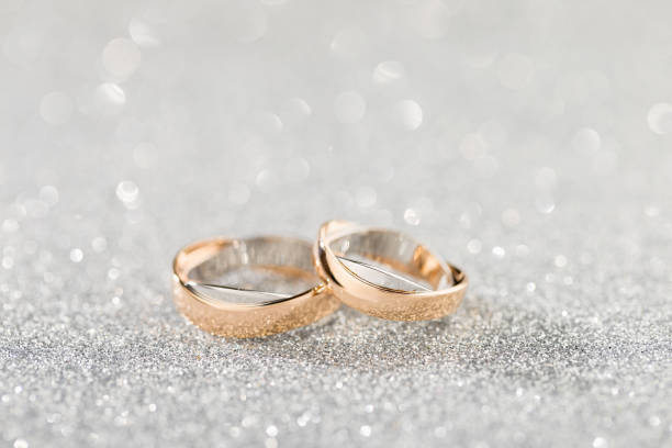 istock Wedding rings on a silver sparkling glitter background with bokeh 941278926