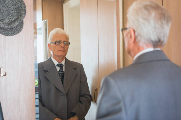 istock Grandfather looking himself at the mirror, getting dresses 941284986