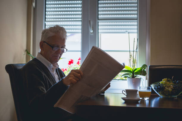 istock Lonesome old man drinking morning coffee, reading newspapers 941284998