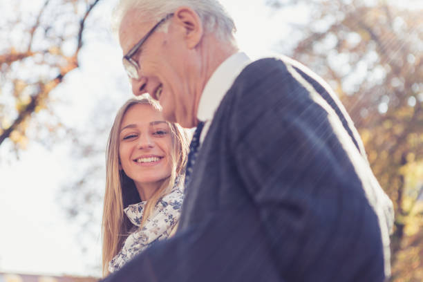 Granddaughter and grandfather walking in the park stock photo