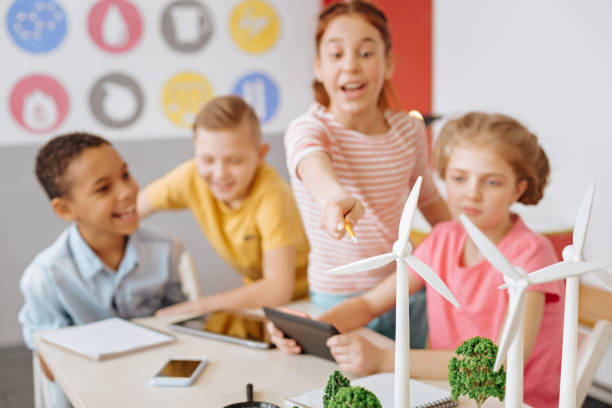 istock Cheerful girl pointing at wind turbines during group discussion 941285032