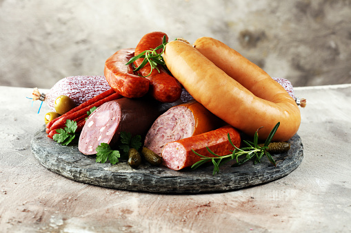 Food tray with delicious salami, ham,  fresh sausages, cucumber and herbs. Meat platter with selection
