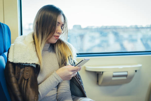 istock Woman traveling by train sitting near window using a mobile phone. 941294596